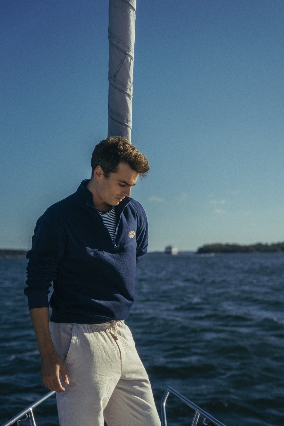A man in the navy Gårdisto Fleece at the bow of a sailing boat in the archipelago