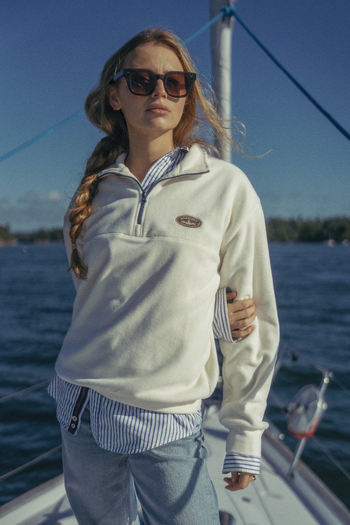Woman in the Gårdisto Fleece Half-Zip in sand on the bow of a sailing boat.