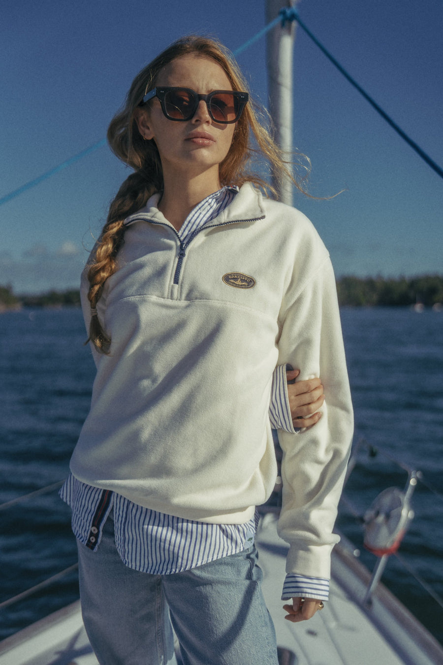 Woman in the Gårdisto Fleece Half-Zip in sand on the bow of a sailing boat.