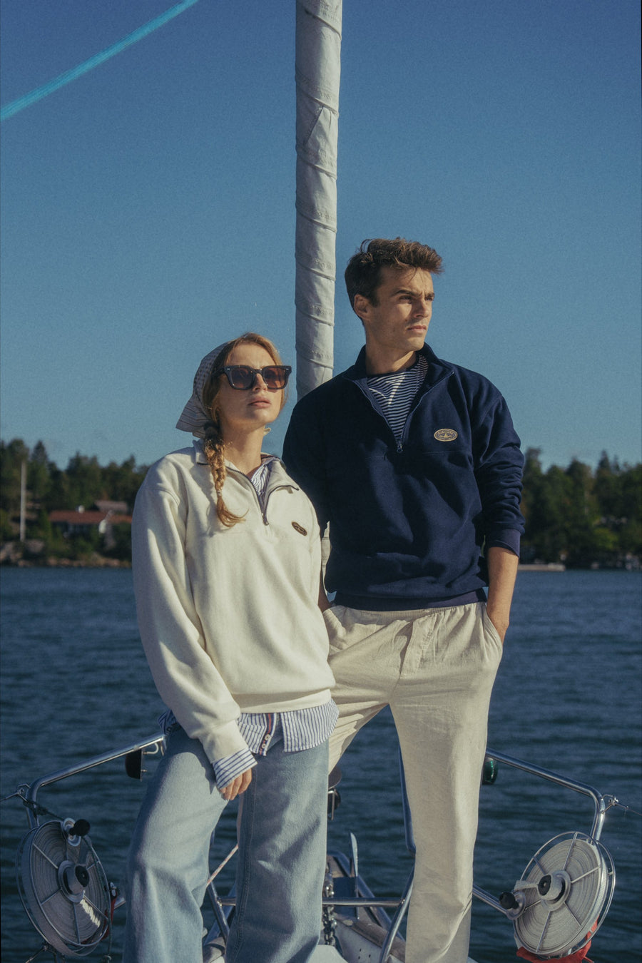 Two people on the foredeck wearing the Gårdisto Fleece Half-Zip in sand and navy.