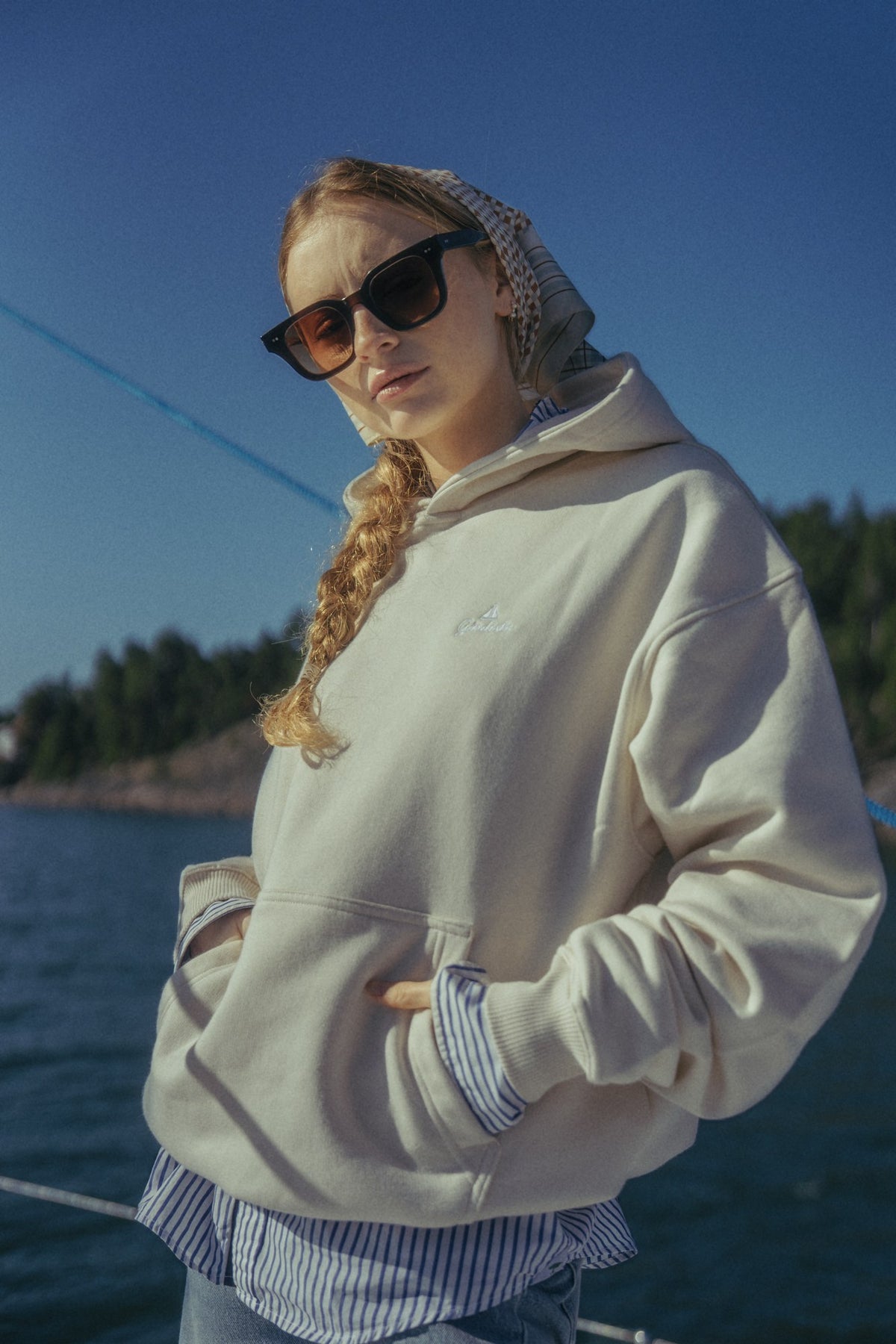 Person i en lys Gårdisto-hoodie på en seilbåt.